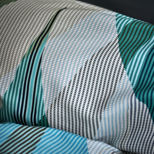 detail shot van een hoofdkussen in een print met groene, blauwe en beige kleuren