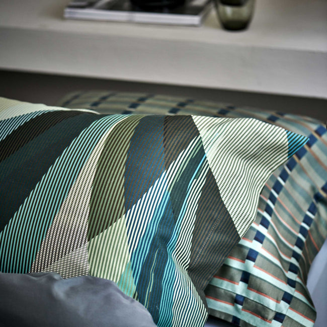 detail shot van een hoofdkussen met strepen en in groene, blauwe en beige kleuren